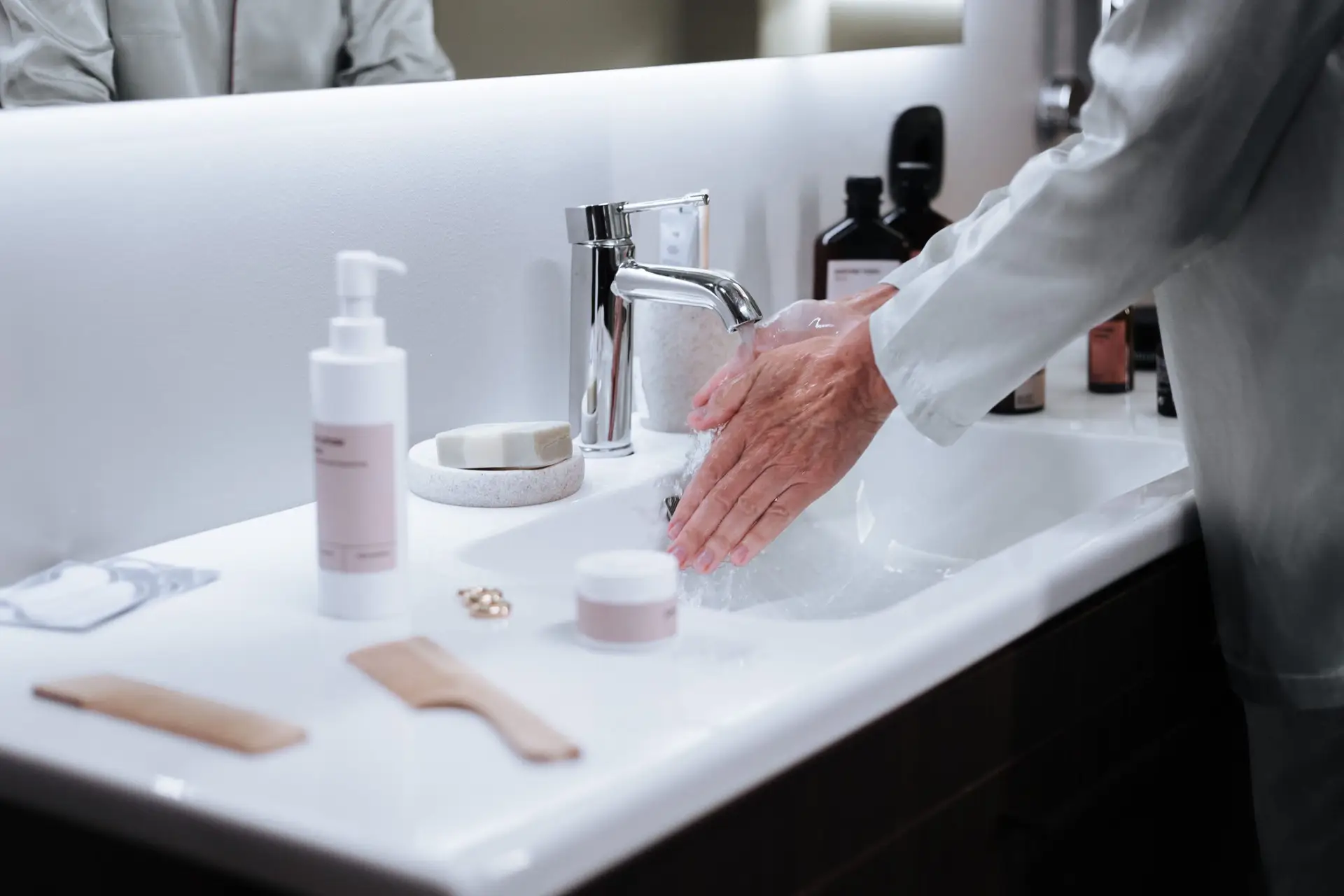Close-up of a man washing hands in a modern bathroom, emphasizing hygiene and cleanliness.